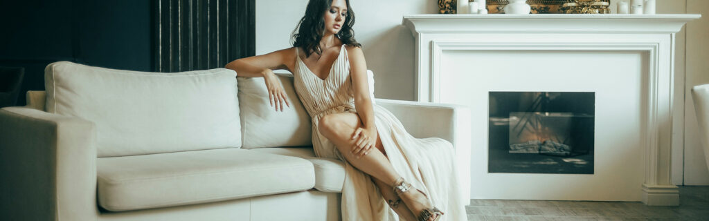 Femme élégante portant des chaussures à talons hauts assise sur un canapé blanc - La Boutique du Haut Talon